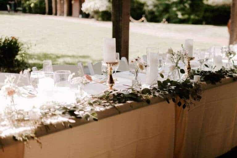 Lush greenery head table runner with high-end flameless LED candles by ILLUME for a wedding reception at Succop Nature Park in Butler, PA.