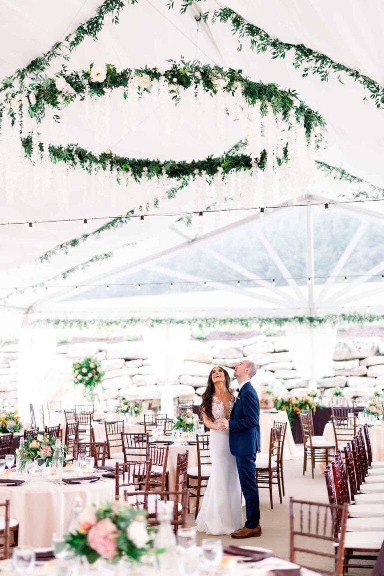 Luxurious full tent draping and a custom suspended floral chandelier by ILLUME for a wedding at The Barn at Maple Falls in Rockwood, PA.