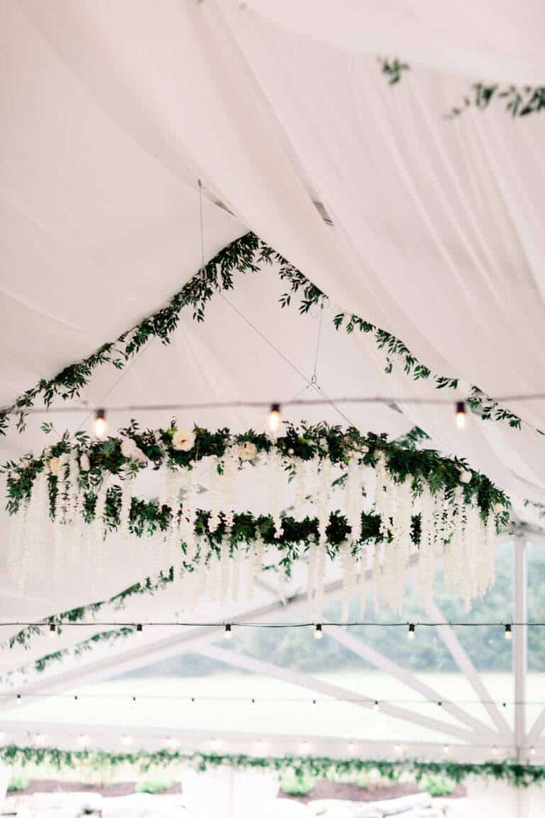 Large suspended floral hoop wreath with greenery and white flowers by ILLUME for a rustic wedding at The Barn at Maple Falls in Rockwood, PA.