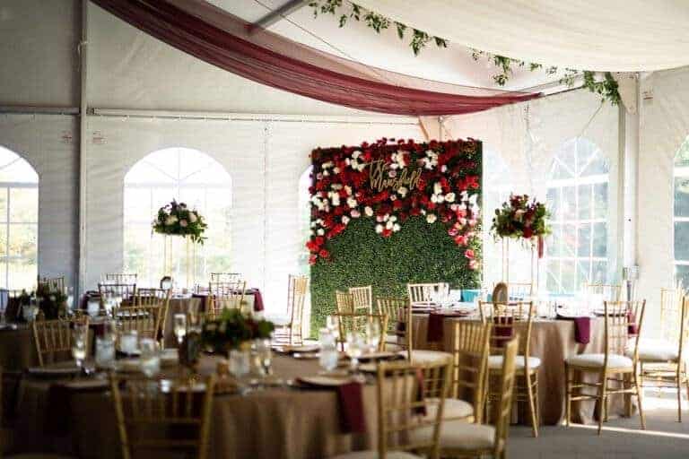 Custom boxwood greenery wall with wood last name sign by ILLUME for a wedding at the historic Linden Hall mansion in Dawson, PA.