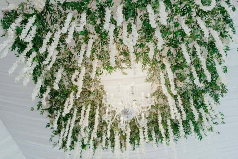 Suspended square floral installation featuring hanging white wisteria and lush greenery by ILLUME for a luxury wedding at Linden Hall.