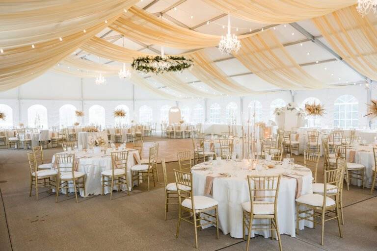 Luxury gold fabric tent draping and a suspended boho-style floral hoop chandelier by ILLUME for a wedding at Linden Hall in Dawson, PA.