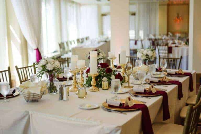 Luxury gold wedding bridal party tablescape featuring gold-rimmed glassware, metallic chargers, and tiered candlelight by ILLUME.