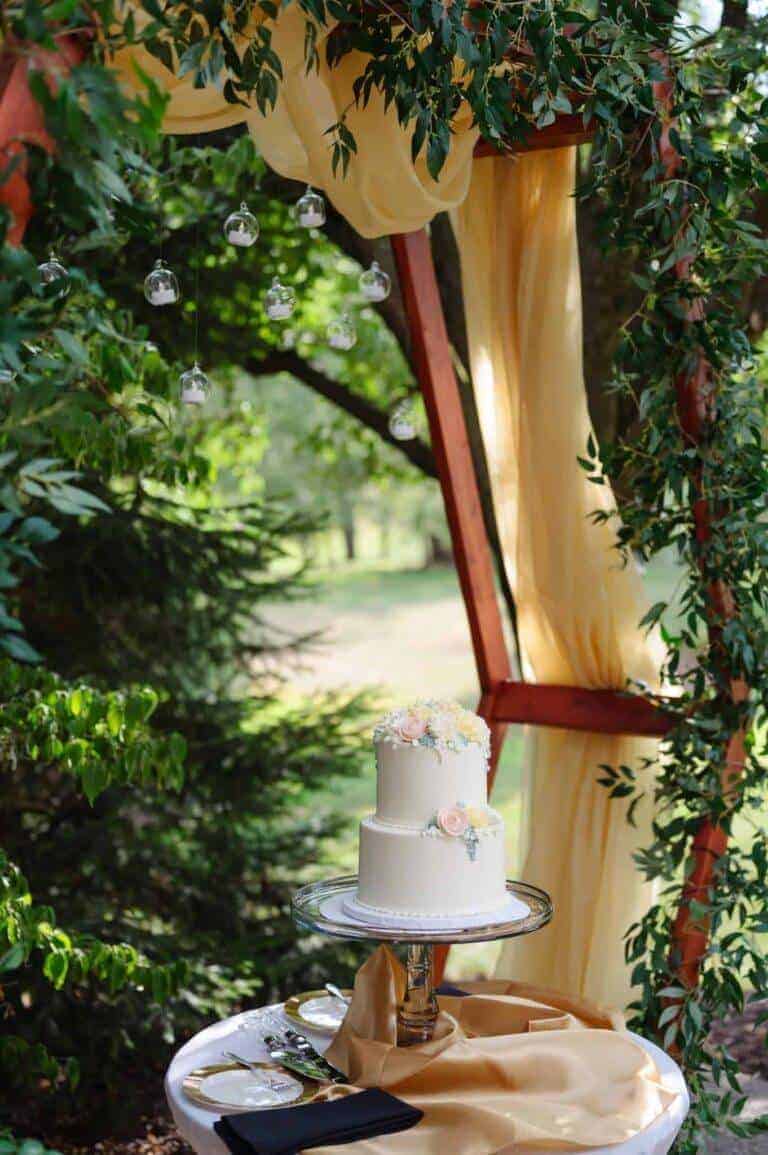 Modern hexagon wedding arbor with gold fabric draping and suspended glass orbs for a luxury backyard wedding in Pittsburgh.
