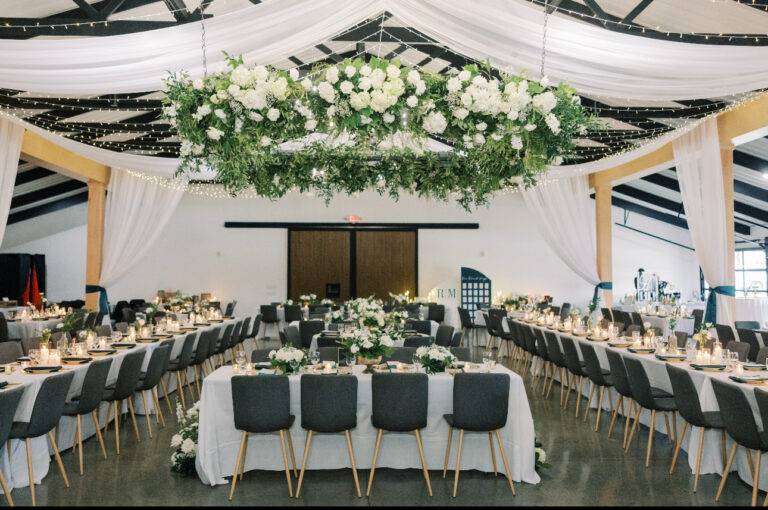 Elegant sheer ceiling draping and warm twinkle lighting design by ILLUME at The Harper event venue in the Meadville area, perfect for a romantic wedding reception.